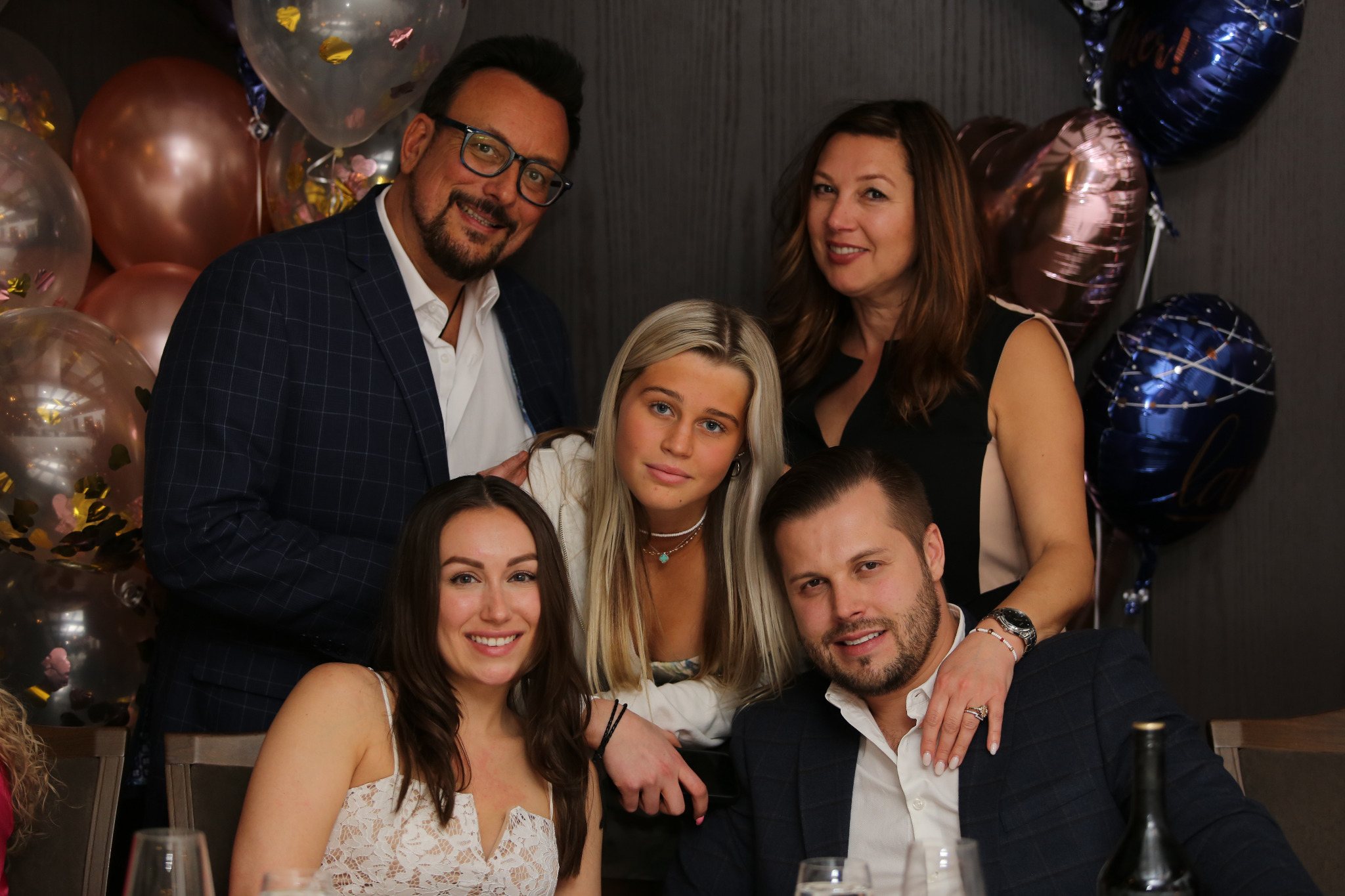 Family group portrait at a celebration with balloons in the background