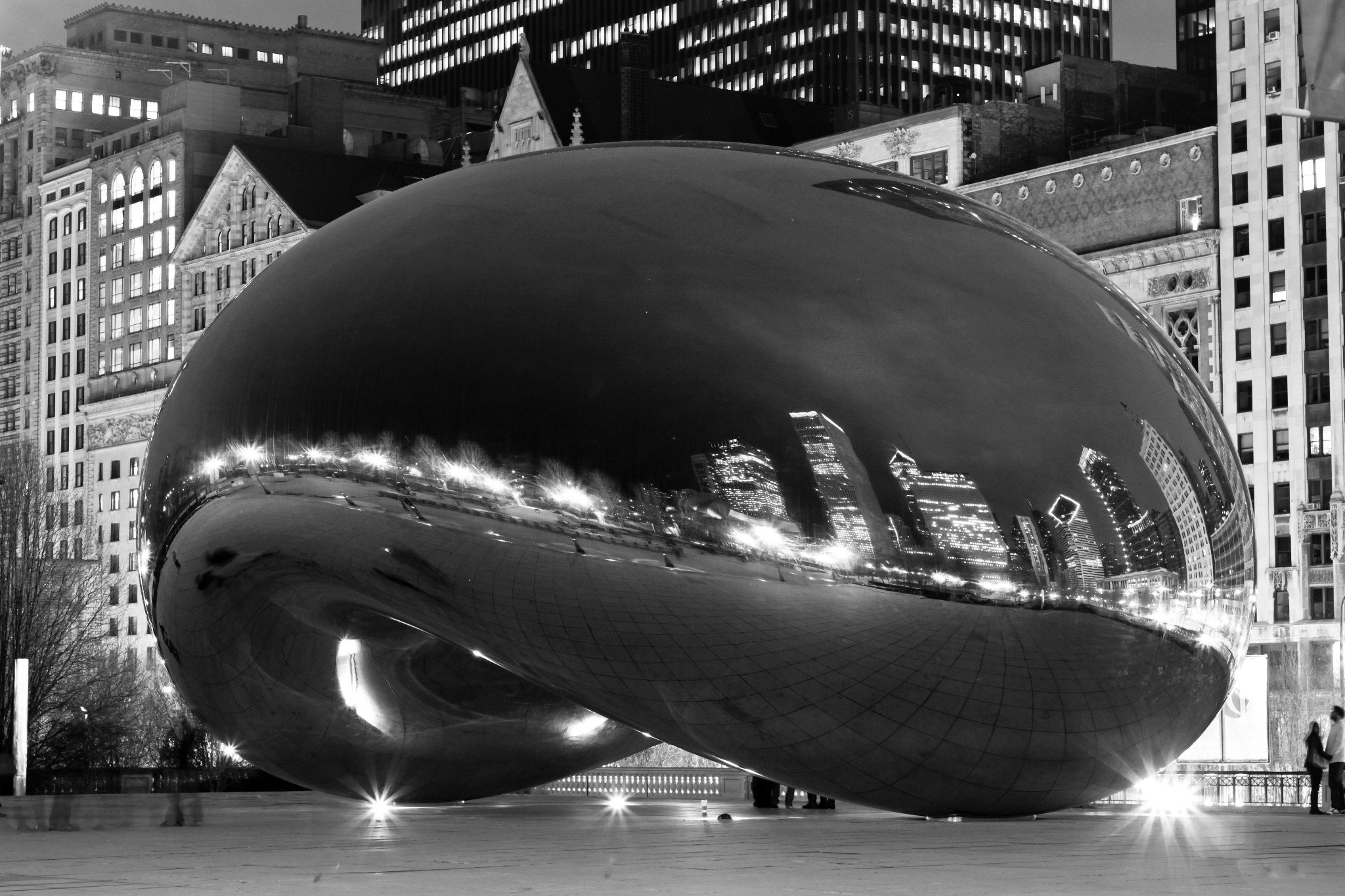 Black-and-white nighttime photograph of Cloud Gate reflecting the Chicago skyline