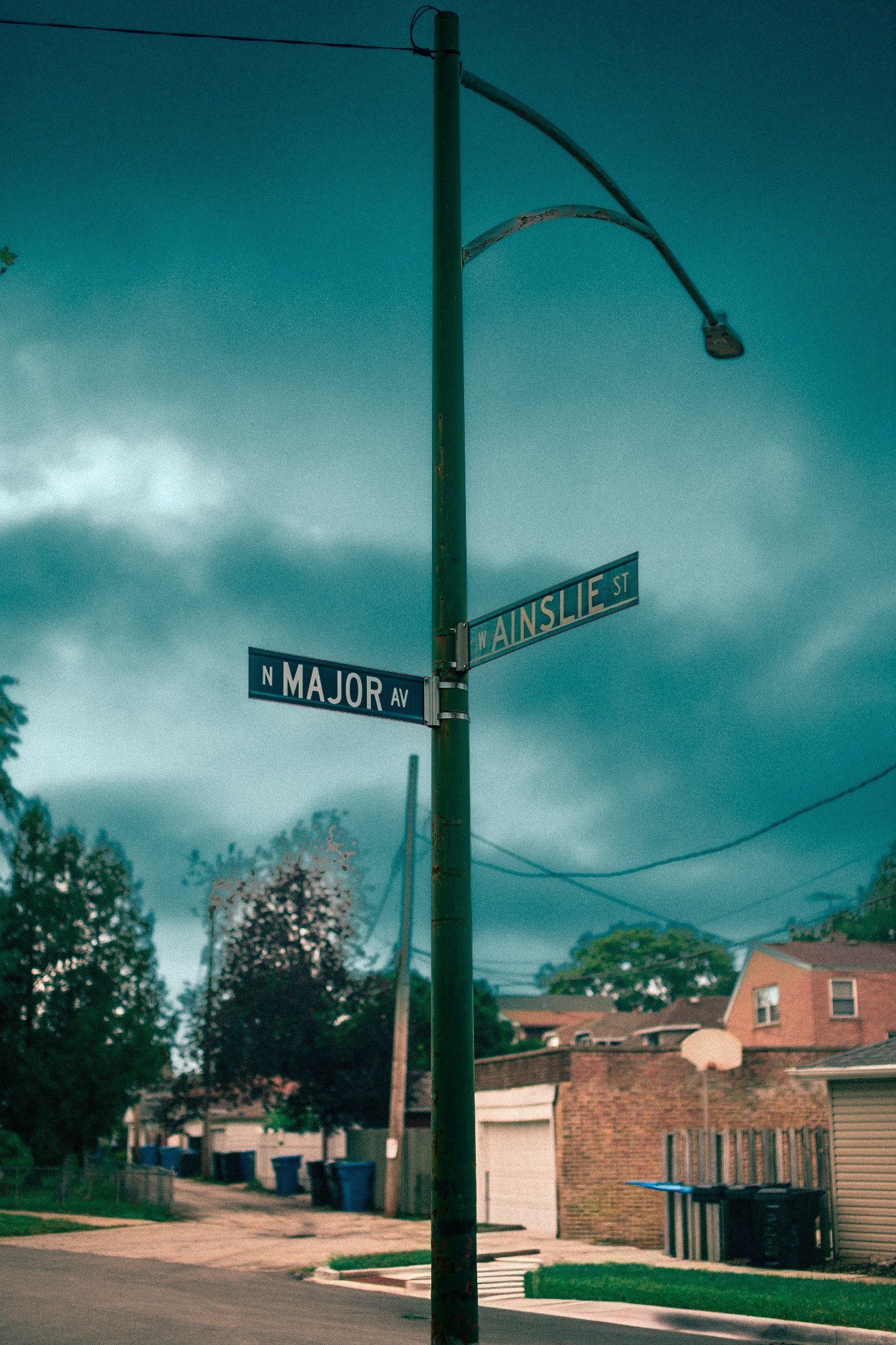 Street signs at Major Avenue and Ainslie Street beneath a dark teal sky