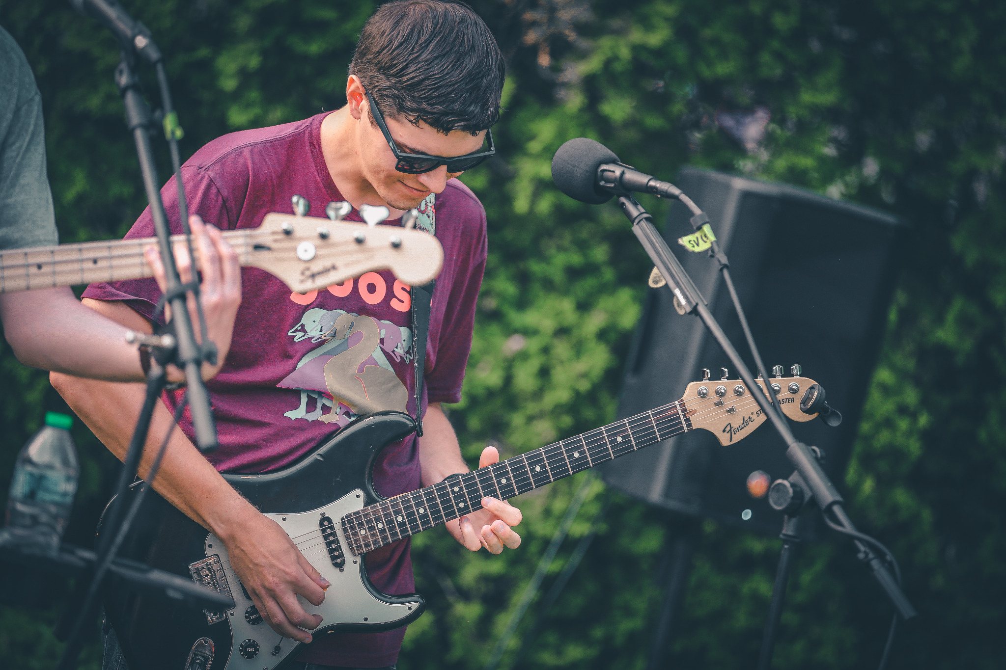 Guitarist performing outdoors beside a microphone and stage equipment